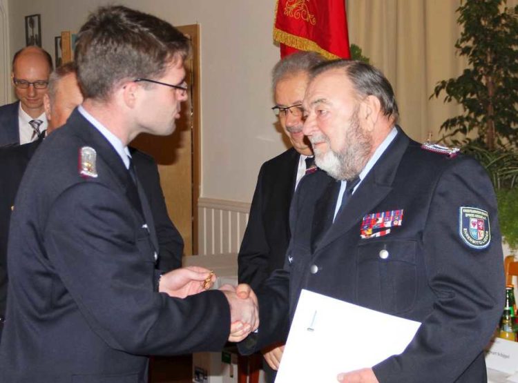 KFV-Vorsitzender Robert Buder steckt Peter Schützke das Ehrenkreuz des DFV in Gold an