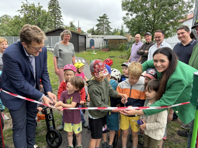 Fürs Band-Durchschneiden bekamen Bürgermeister Andreas Pfeiffer (l.) und Geschäftsführerin Elisabeth Bruckmoser (r.) ganz viel Hilfe von den Bienenschwarm-Kindern. Sie wollten am Mittwochvormittag nur eins: ganz schnell rauf auf die Rollerbahn und Tempo machen! (Bild: Andrea Budich)