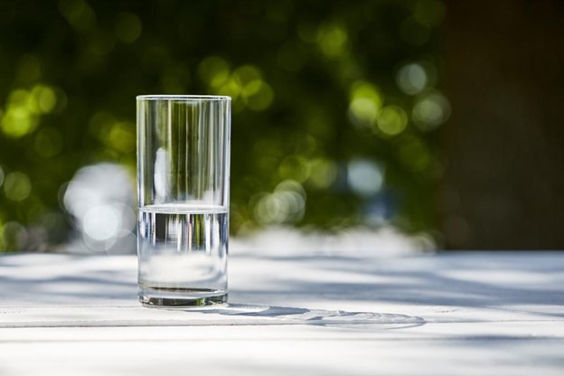 Ein Glas Wasser auf einem Tisch an einem sonnigen Tag