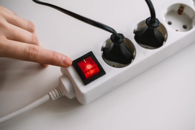 Hand turns on an electric surge protector. Protection of household appliances from electrical interference. Home safety